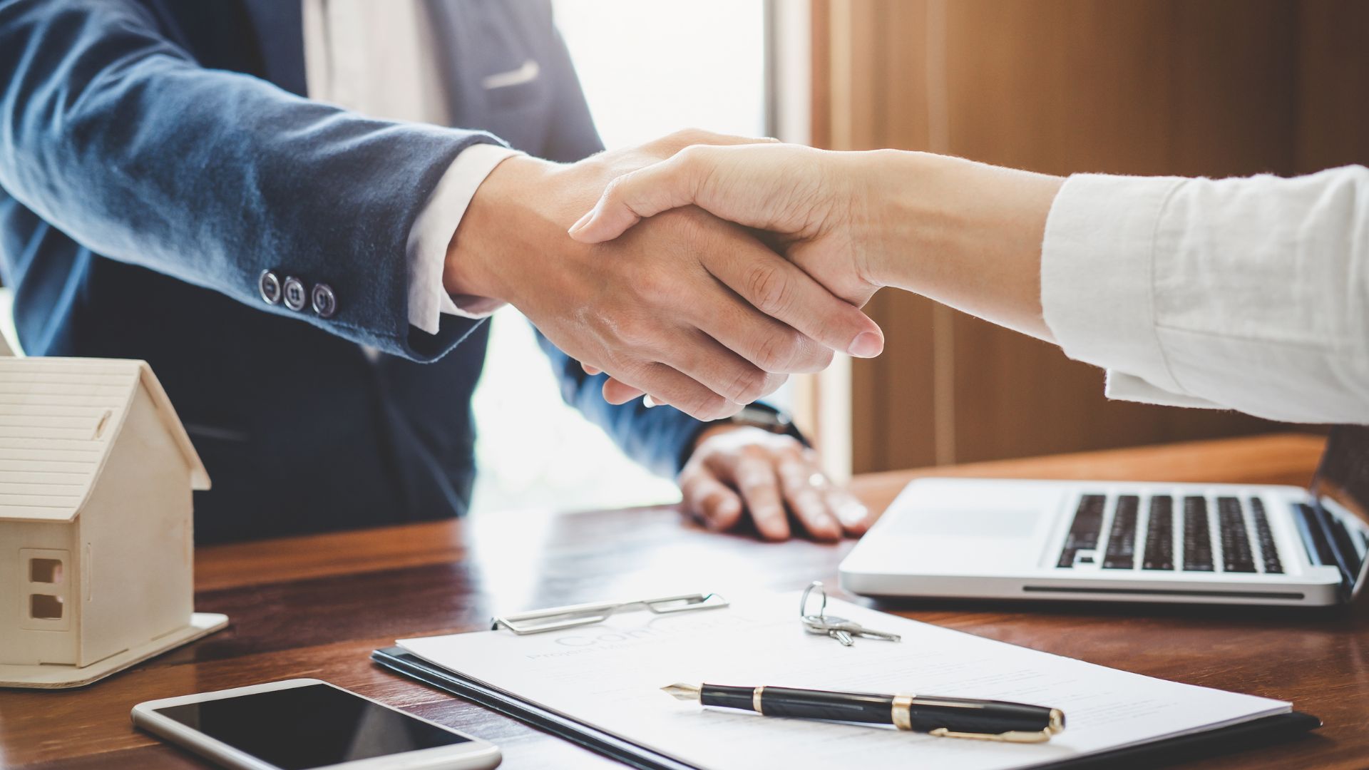 two people shaking hands across a desk